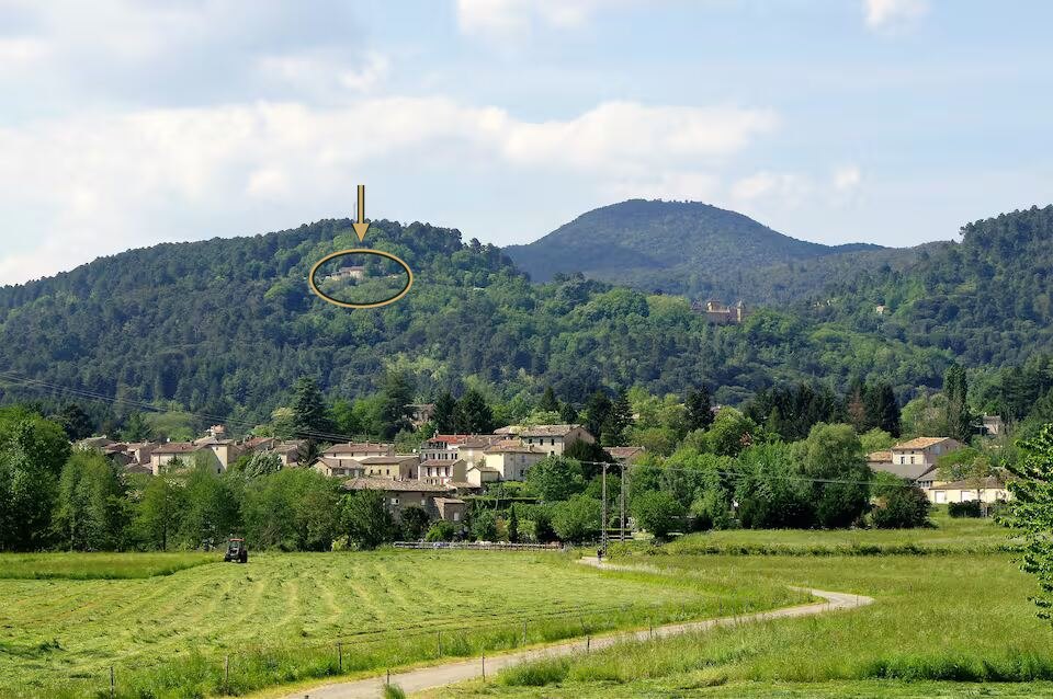 Le Mas de Clarou, entouré d’un cercle sur la photographie : il est perché sur une colline boisée au-dessus du village de Lasalle, vu depuis le village